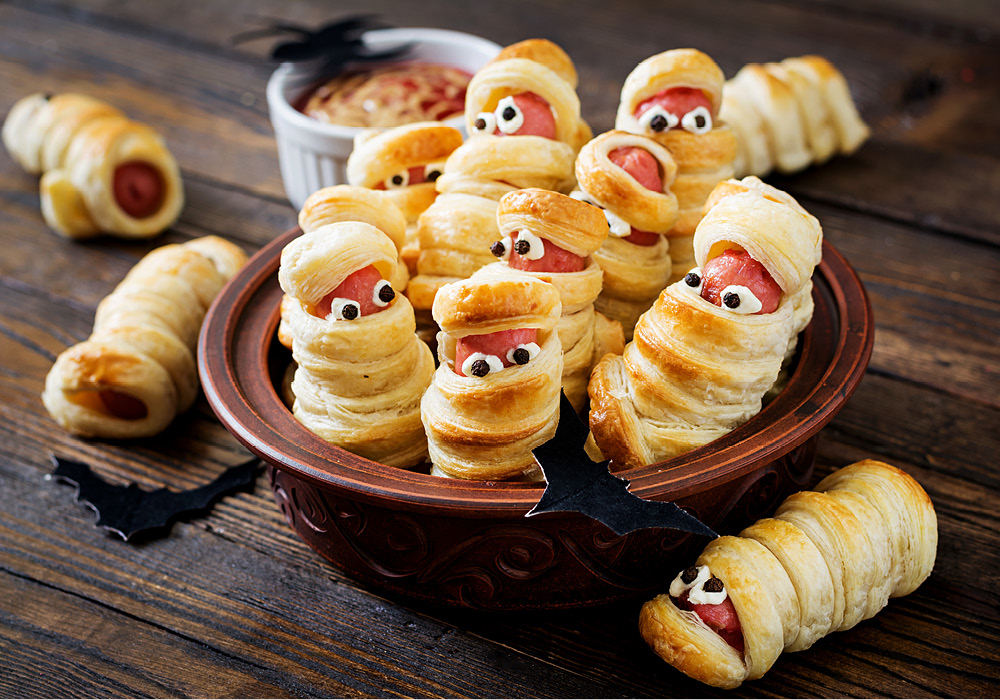 Tiny Halloween-inspired mummified hot dogs in a bowl.