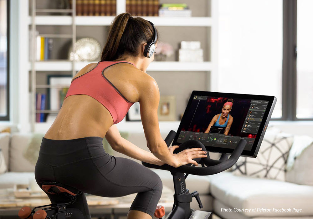 Woman on a Peloton bike exercising in her apartment home.
