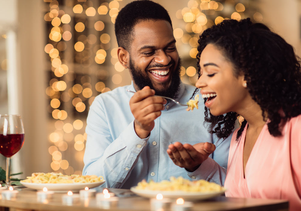 Man feeding woman a romantic Valentine's Day dinner.