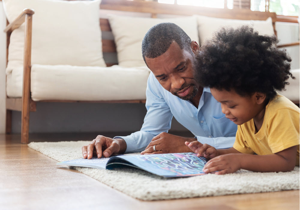 Father and son relaxing in their apartment with a book.