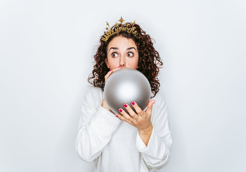 Woman blowing up silver balloon for the holidays.