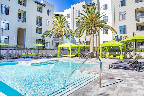 Outdoor swimming pool and sundeck with lounge chairs and poolside cabanas.