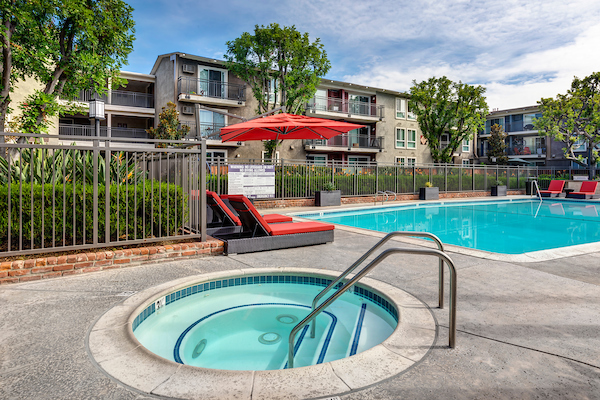 Outdoor spa and swimming pool area with lounge seating and umbrella.