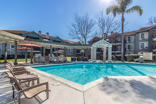 Outdoor swimming pool area with sundeck and lounge seating under pergola.