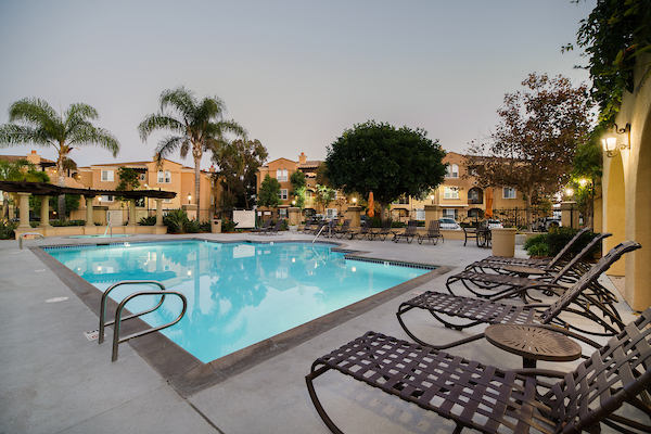 Outdoor swimming pool area with lounge seating at dusk.