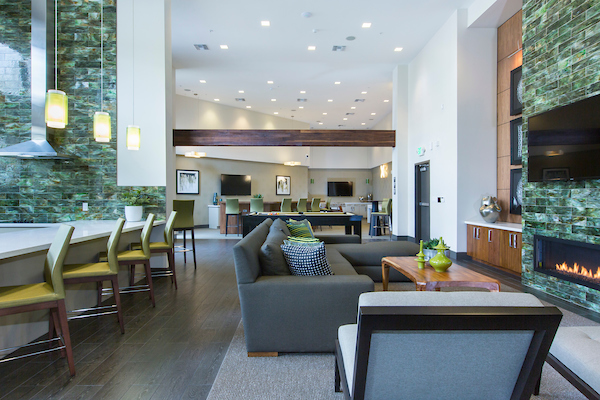 Clubhouse with bar seating, fireplace,pool table, kitchen, sofa, and chairs.
