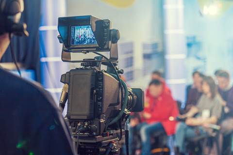 Cameraman recording seated people.